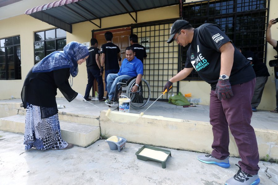 General Manager of Petronas East Coast Region, Wan M Hasnan Abdullah (right) and General Manager of the Kelantan Foundation for Disabled (YOKUK), Sulaini Mat with the staff and some students of SMK Wakaf Bharu cleaning up the YOKUK building area as part of Sentuhan Kasih Ramadhan in Pengkalan Chepa. Pix by Zaman Huri