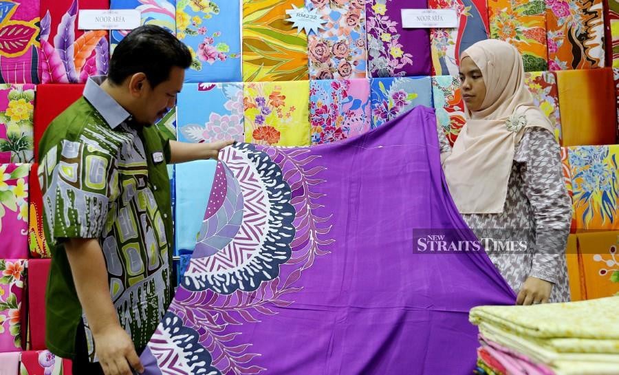 Noor Arfa Batik managing director Wan Mohd Hafiz Wan Mohd Ariffin (left) checks on some of the batik on display at the Noor Arfa Craft Complex in Chendering. -NSTP