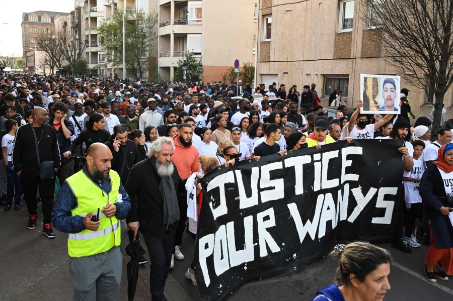 People hold banners reading 'Justice for Wanys and Ibrahim' during a 'Marche Blanche' (White March) held to pay tribute to  eighteen year-old Wanys R. who was killed while riding a scooter pursued by police after refusing to stop. A white march has taken place in La Courneuve (Seine-Saint-Denis) to pay tribute to Wanys, who was killed last week in a collision with a police car in the neighbouring town of Aubervilliers. — AFP