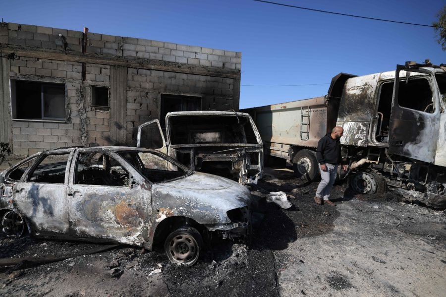 A Palestinian inspects the damage to vehicles in the village of Mughayir near Ramallah in the Israeli-occupied West Bank on April 13, 2024, set ablaze by Israeli settlers during an attack on the village. - AFP pic