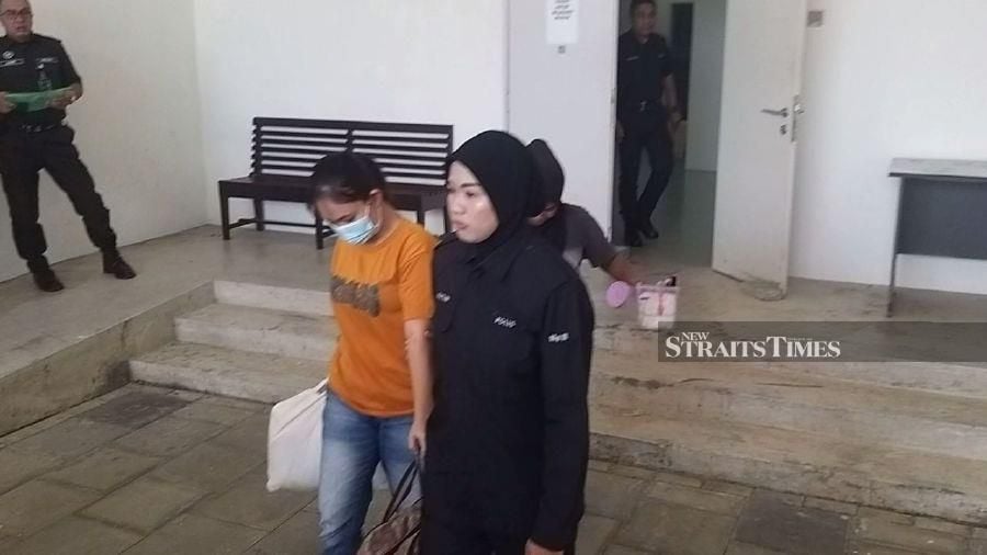 Yuni Widya Sari (left) seen arriving at the Kangar magistrate’s court ahead of the trial.-NSTP/AIZAT SHARIF