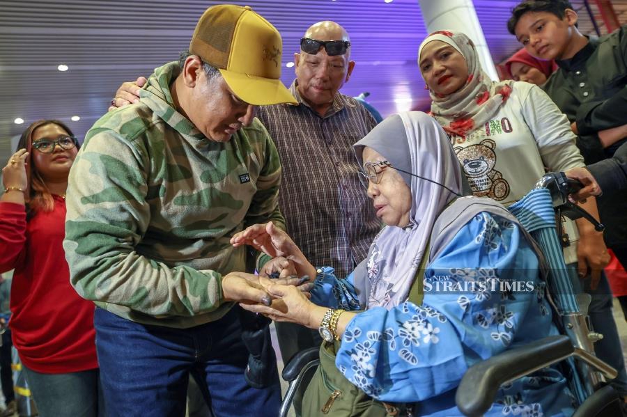  Zainudin shows injuries to his hands caused by frostbite to mother Jasidah Hamid, 73, at the Kuala Lumpur International Airport (KLIA)-- fotoBERNAMA 