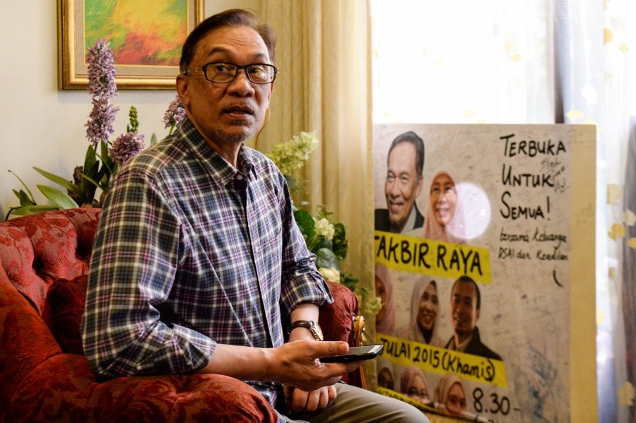 Leader of the Pakatan Harapan coalition, Anwar Ibrahim holds his mobile phone at his house in Kuala Lumpur on May 17, 2018.  AFP PHOTO