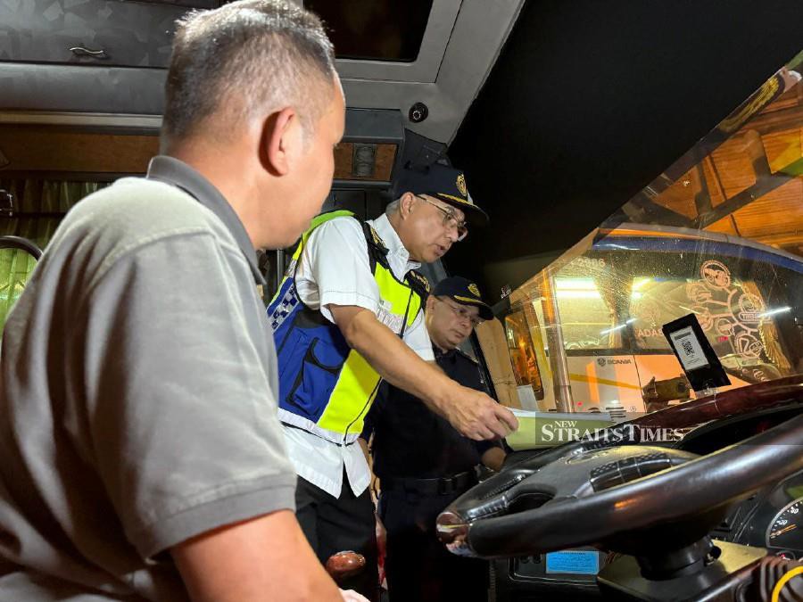 RTD senior director (enforcement) Datuk Lokman Jamaan inspecting an express bus driver during the department’s Hari Raya Aidilfitri operation in Alor Star last night.