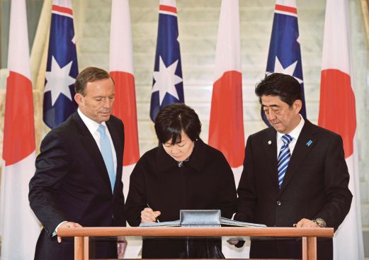 Akie Abe (C) signs the visitors' book with Australian Prime Minister Tony Abbott (L) and Japanese Prime Minister Shinzo Abe (R) at Parliament House in Canberra. AFP PHOTO
