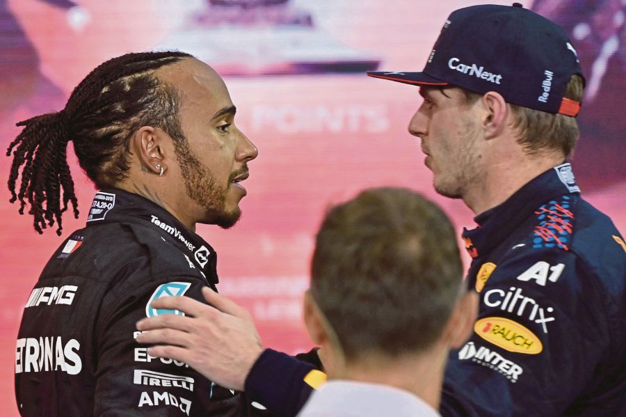 2021 FIA Formula One World Champion Red Bull's Dutch driver Max Verstappen (right) greets second-placed Mercedes' British driver Lewis Hamilton (left) after the Abu Dhabi Formula One Grand Prix at the Yas Marina Circuit on December 12, 2021. - (Photo by ANDREJ ISAKOVIC / AFP)