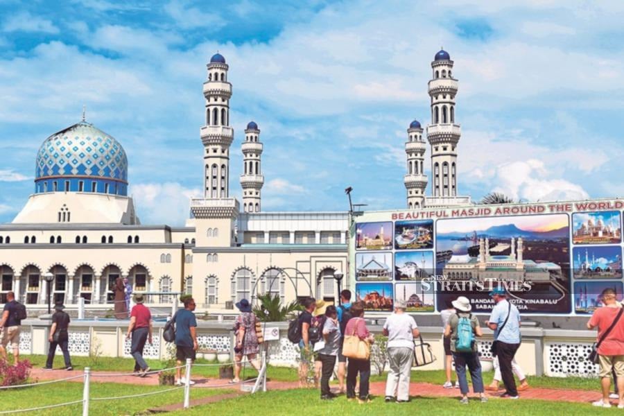 Cruise passengers taking pictures in front of the iconic City Mosque in Kota Kinabalu recently. -NSTP/MOHD ADAM ARININ