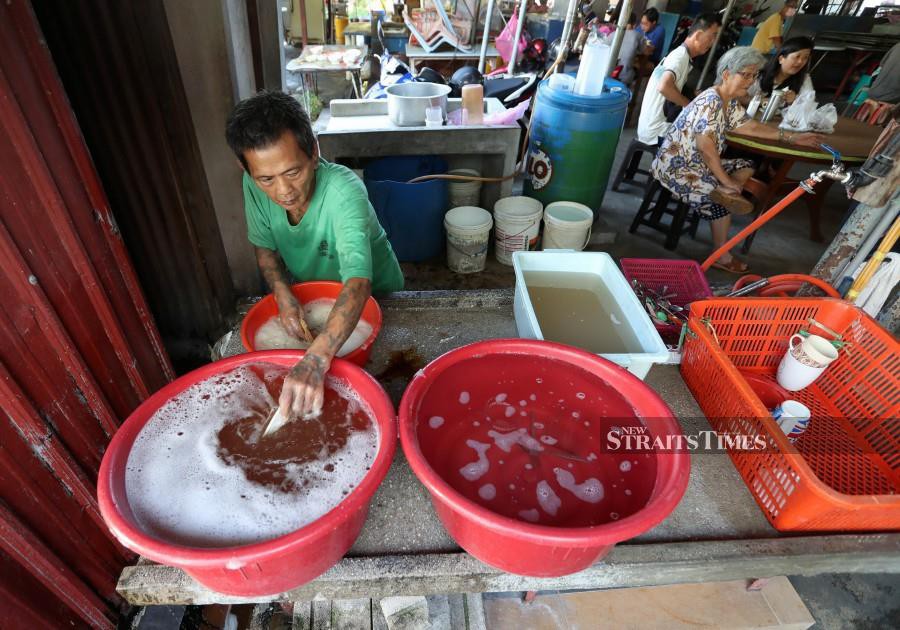A trader washes his kitchen utensil from water he had saved, due to the disruption in George Town. -NSTP/MIKAIL ONG