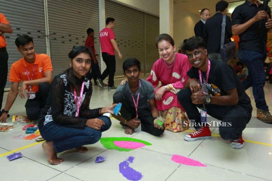 Malaysian AEON Foundation president Datin Yasmin Merican and AEON employees sharing in the joys of Deepavali with children from the Damo Children Home, Kluang in a kolam design activity at AEON BiG, Kluang on Oct 19.