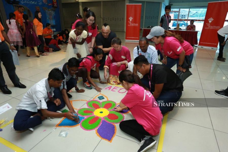 Sharing in the joys of Deepavali with AEON. Malaysian AEON Foundation president Datin Yasmin Merican (centre), Damo Children Home founder S. Damodran (right) and Cross Community director Jit Pang Lim (left), with AEON employees participating in a kolam design competition at the AEON BiG Mall in Kluang, Johor. 