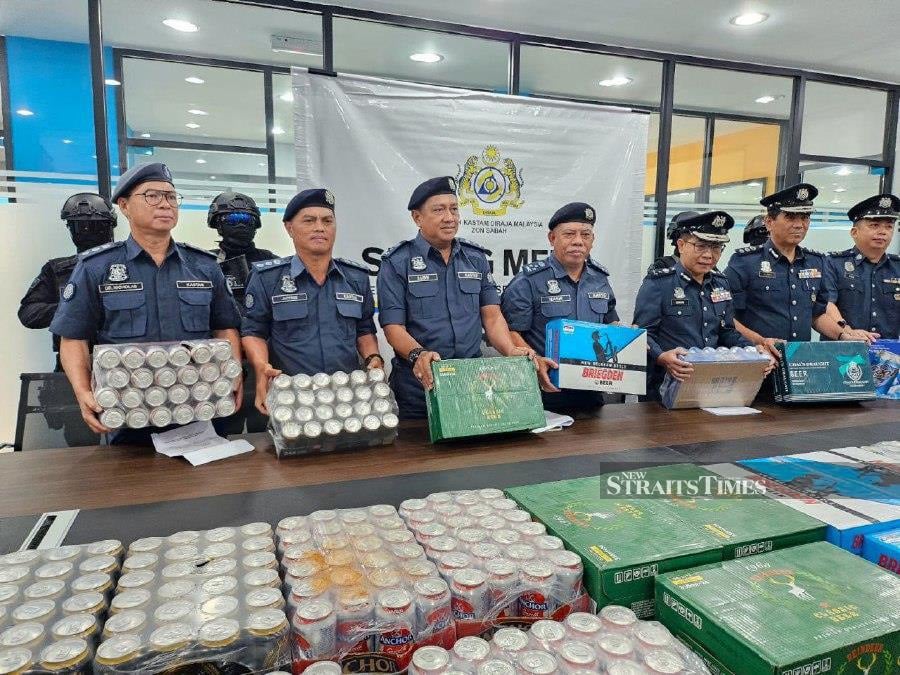 Sabah Customs Department assistant director-general Datuk Mohd Nasir Deraman and his officers with some of the smuggled liquor seized in an operation recently. NSTP/JUWAN RIDUAN