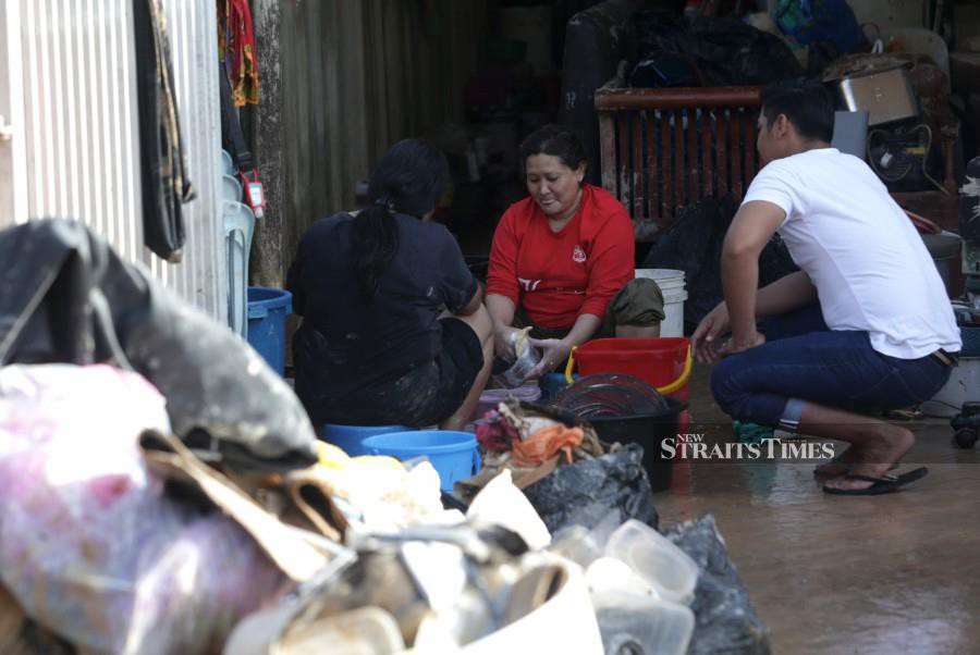 Residents seen cleaning their belongings this morning. -NSTP/MOHAMAD SHAHRIL BADRI SAALI