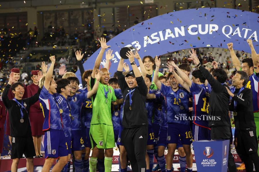 Japan coach Go Oiwa lifts the trophy as players cheer after winning the Under-23 Asian Cup final against Uzbekistan at Jassim Bin Hamad Stadium in Doha on Friday. - AFP PIC