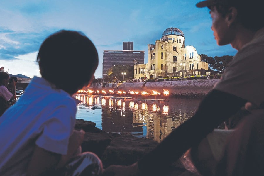 People watching lanterns being lit and placed on the Motoyasu river by the Atom Bomb Dome last Saturday, to mark the 78th anniversary of the world’s first atom bomb attack in Hiroshima on Aug 6, 1945. - Pic by JIJI Press / AFP