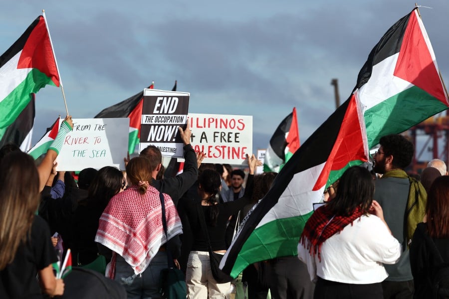 Australian Palestinian community members holding flags and placards during a protest at the Port Botany terminal in Sydney on Nov 21. Police announced on Nov 22 they have charged 23 people from the protest, claiming they tried to block a road leading into the port facility. AFP pic
