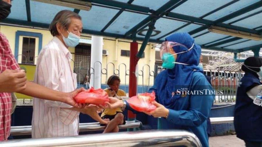 Johor Bersatu Srikandi chief Azlinda Latif giving out food packages under the Street Kitchen programme.