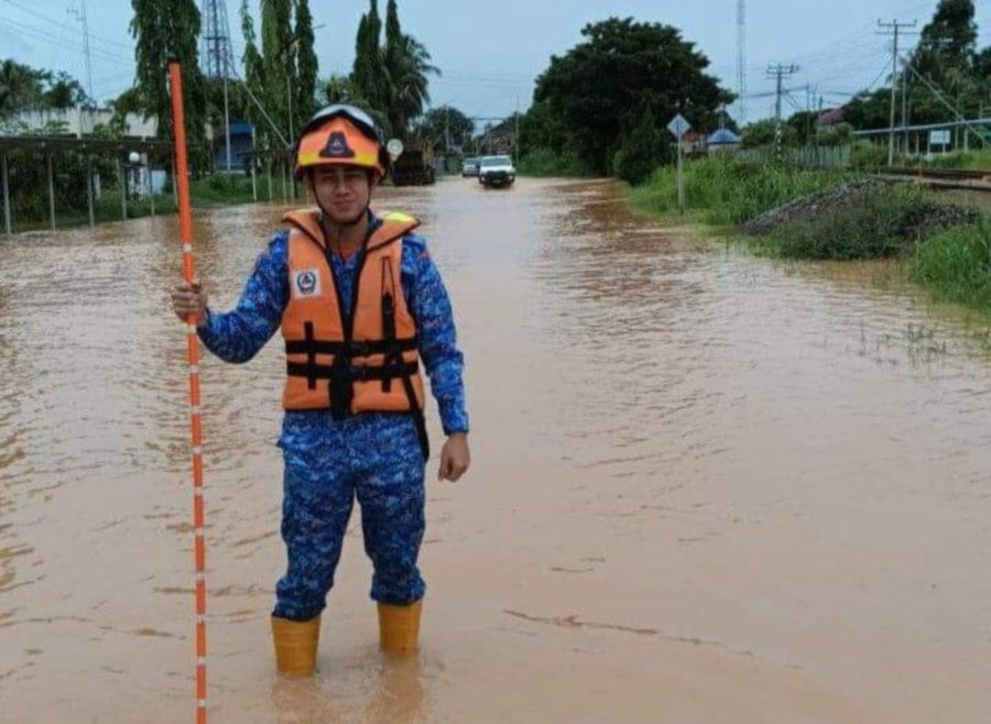 A Civil Defence Force personnel checking the water level along a road in Membakut following a flood. -- Pic courtesy of APM