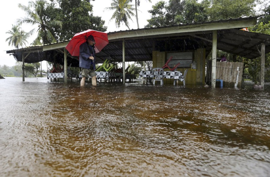 PASIR PUTEH: A man inspecting his food stall along Jalan Kampung Dalam Ru. Two flood relief centres were opened in the district today making it the first district in Kelantan affected by the floods. -- NSTP/NIK ABDULLAH NIK OMAR