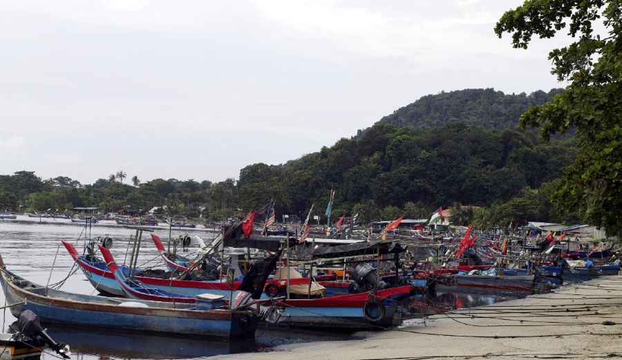 BALIK PULAU: Fishing boats stranded near Jeti Nelayan Teluk Kumbar following a low tide incident. Fishermen are taking this opportunity to repair on their boats and fishing nets. -- BERNAMA PIC