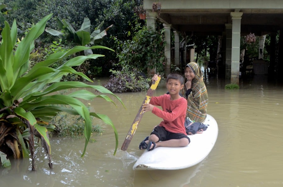 Two siblings Dani Roduan, 8, and Nur Daliya, 11, using a kayak to move around as their house inundated following heavy rain since Wednesday.- Bernama pic