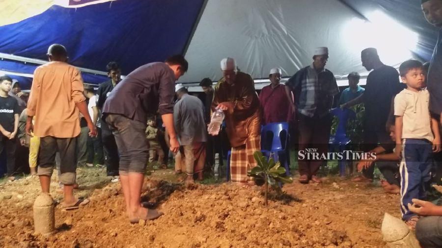 Salleh Eizan pours rose water during the funeral at Masjid Putra Muslim Cemetery, Simpang Empat, Kangar. - NSTP/AIZAT SHARIF