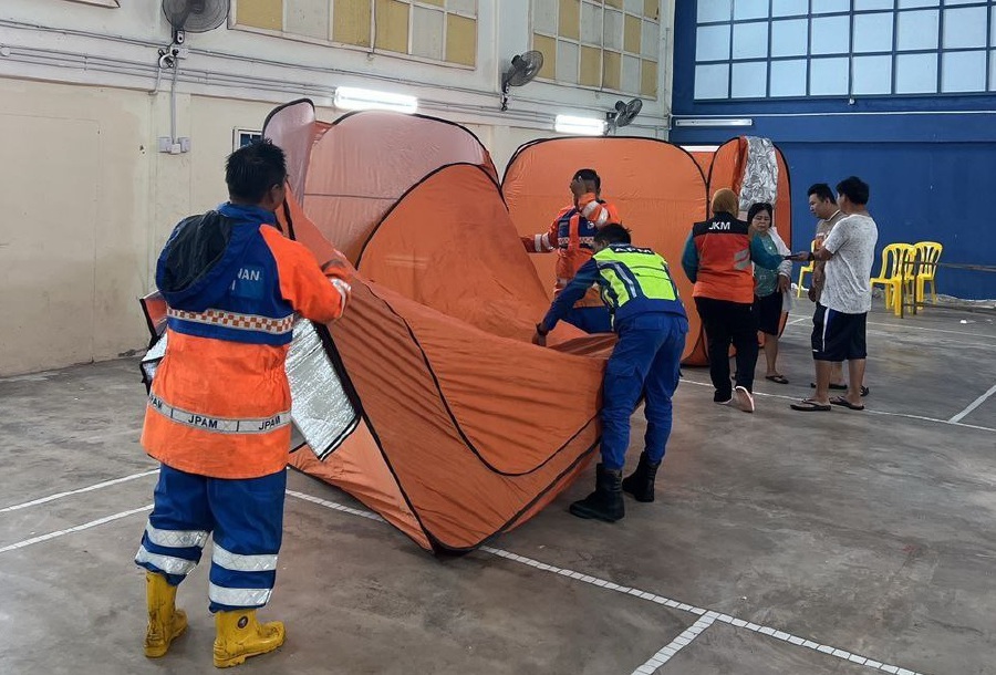 Bera district Civil Defence Force assisting flood victims to move to the relief centre at Kemayan public hall today. - Pic courtesy of APM