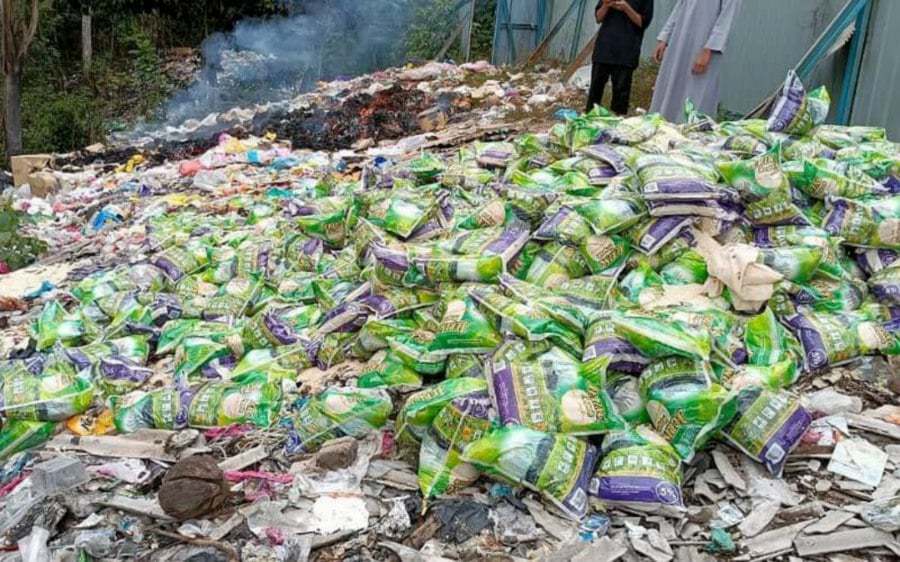Images and videos of the allegedly disposed and burning sacks of rice and cans of sardines, as well as large amounts of unopened packages of tea at a garbage disposal site in Temerloh. - Pic courtesy of reader