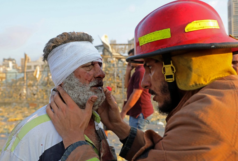 A wounded man is checked by a fireman near the scene of an explosion in Beirut. -AFP pic