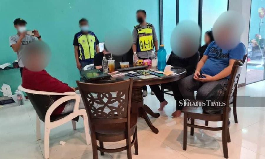 Some of the suspects being questioned by police officers during the raid at a luxury residential area in Jalan Stutong, Kuching. - NSTP/NORSYAZWANI NASRI