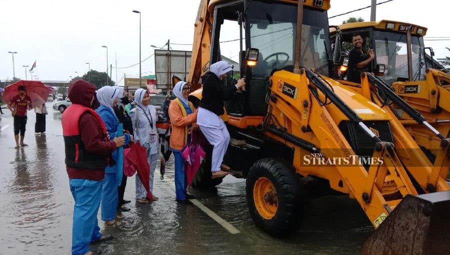 Determined healthcare workers at Hospital Hulu Terengganu (HHT) utilised excavators to reach their patients after light vehicles were unable to traverse floods. - NSTP/Nazdy Harun