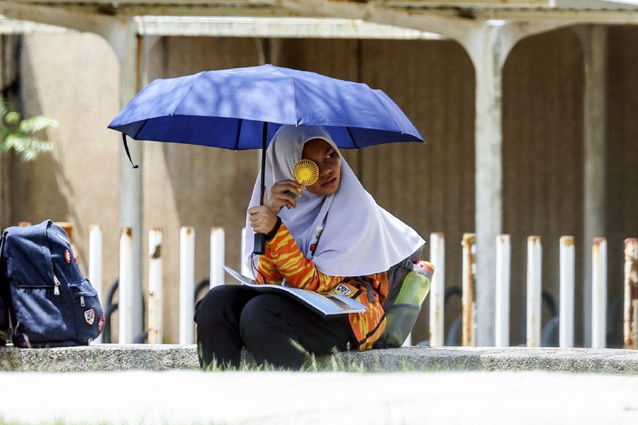 PUTRAJAYA: A female school student uses an umbrella and a handheld mini fan to keep cool in the vicinity of Sekolah Menegah Kebangsaan Putrajaya Precint 9 (2) on Thursday (May 11) as the temperature recorded at the time was 33 degrees Celsius. Members of the public have been advised to keep themselves hydrated by drinking at least eight glasses of water a day during the current hot and humid weather spell. -BERNAMA PIC