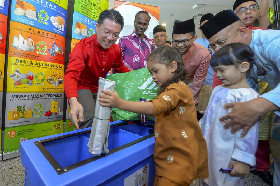 PUTRAJAYA: Local Government Development Minister Nga Kor Ming is all smiles as he shows some children the correct way to separate waste for recycling during the Local Government and Development Ministry's Hari Raya Aidilfitri open house here in Putrajaya on Thursday (May 11). -BERNAMA PIC