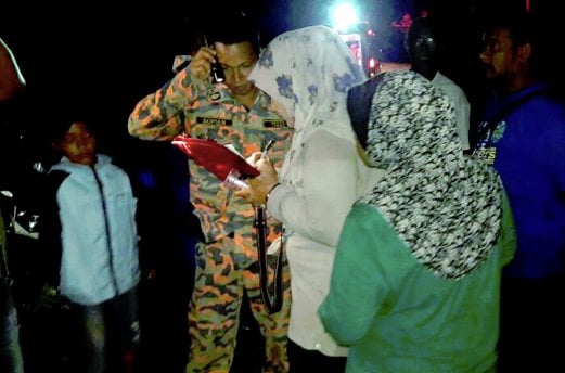 (File pix) A fireman on search and rescue duty at Bikit Mertajam getting information about four missing hikers yesterday. The four hikers were found last night at a trail checkpoint. Pix courtesy of Fire and Rescue Department
