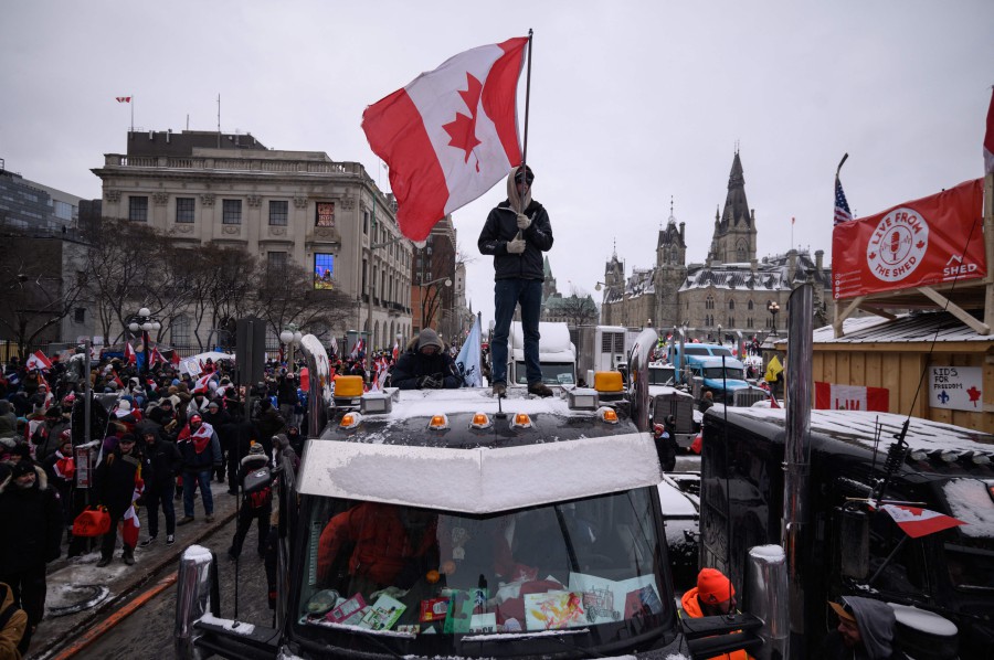  A demonstrator stands atop a truck holding a Canadian flag during a protest by truck drivers over Covid-19 mandates, outside the parliament of Canada in Ottawa. - AFP PIC