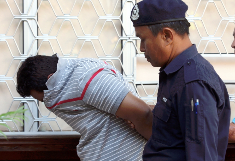 The 42-year-old accused (left) is escorted by a police officer at the Kota Baru Session’s Court. Pic by ZAMAN HURI ISA
