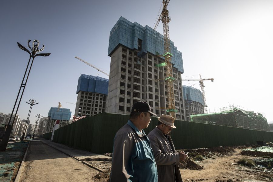 Pedestrians near apartment blocks under construction in the Nanchuan area of Xining, Qinghai province, China, on Tuesday, September 28, 2021. Photographer: Qilai Shen/Bloomberg