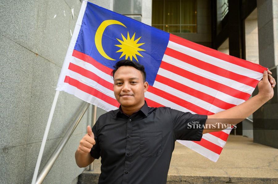 Formerly stateless eSports player Muhammad Aiman Hafizi Ahmad poses with a Malaysian flag after receiving his Malaysian citizenship certificate outside the National Registration Department building in Putrajaya. Muhammad Aiman Hafizi, a rising eSports star was granted Malaysian citizenship on September 1, after a lengthy battle, in a victory that will pave the way for him to compete internationally. AFP photo
