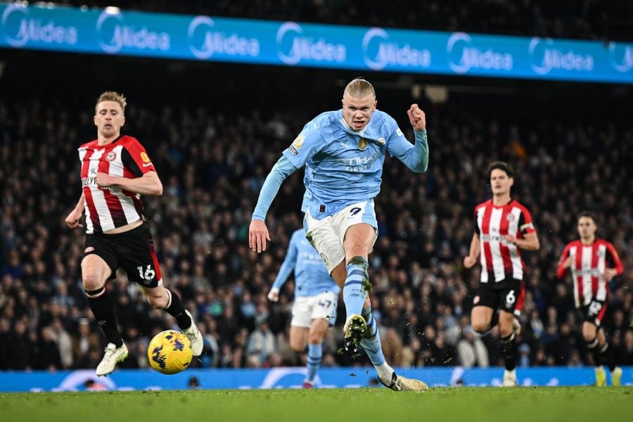 Manchester City's Norwegian striker Erling Haaland shoots and scores his team first goal during the English Premier League football match between Manchester City and Brentford at the Etihad Stadium in Manchester, north west England. (Photo by Paul ELLIS / AFP) 