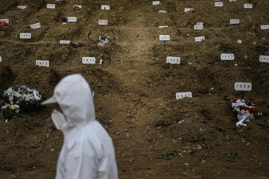 A grave digger wearing a protective suit walks past graves during the burial of a Covid-19 victim at the Alto de Sao Joao cemetery in Lisbon, Portugal. AFP pic.