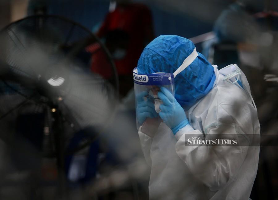 This file pic dated Nov 21, shows a medical officer putting on a face shield before conducting Covid-19 screening in Klang. -NSTP/ASWADI ALIAS.