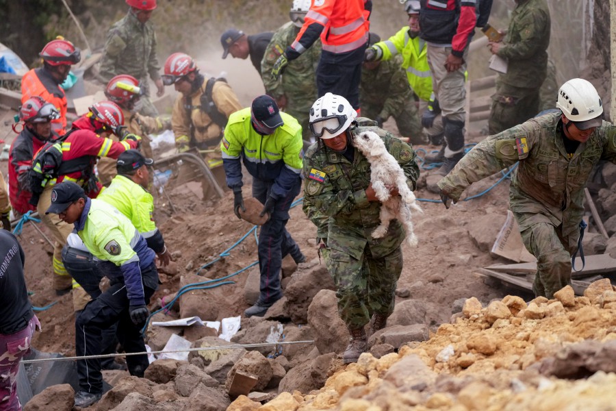 A soldier carries a dog found among the rubble of buildings destroyed by a deadly landslide that buried dozens of homes in Alausi, Ecuador. --AP PIC