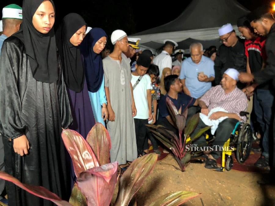 Noor Rahiza Anuar’s children at the Masjid Haji Nyak Gam’s Muslim Burial Ground in Kampung Ruat. -- NSTP/ZULIATY ZULKIFLI