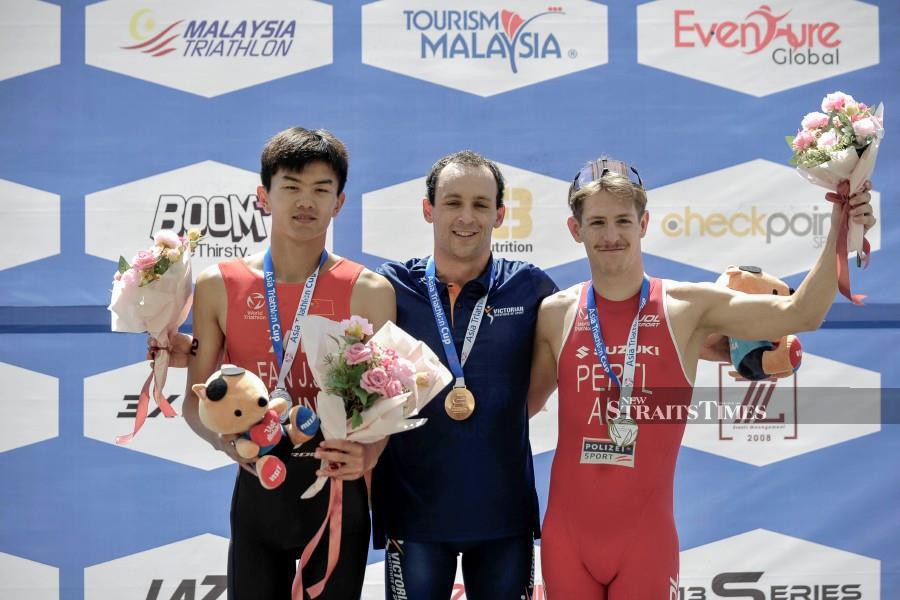 Christopher Deegan (centre) with Junjie Fan (left) and Philip Pertl pose for a group photo after the Asia Triathlon Cup Putrajaya at the Putrajaya Watersports Complex. - NSTP/AIZUDDIN SAAD