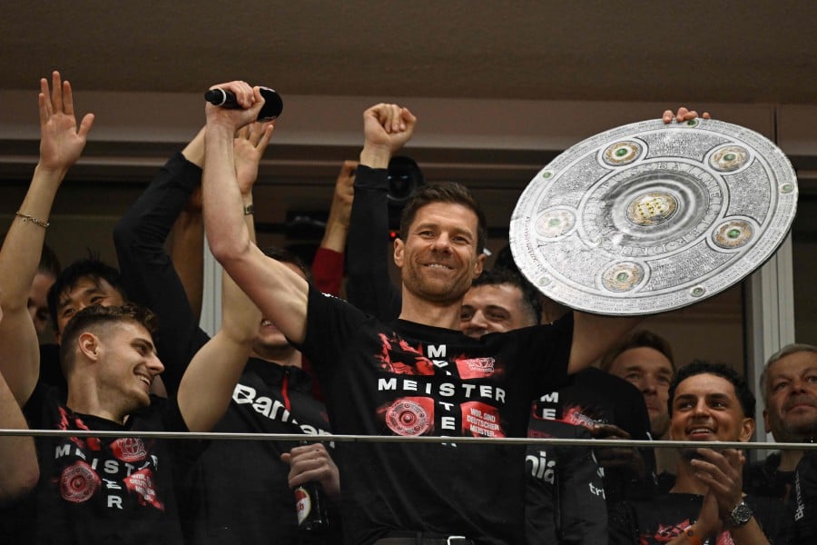 Bayer Leverkusen's Spanish head coach Xabi Alonso celebrates with a mock-up of the Bundesliga trophy with his players after the German first division Bundesliga football match Bayer 04 Leverkusen v Werder Bremen in Leverkusen, western Germany, on April 14, 2024. -- AFP