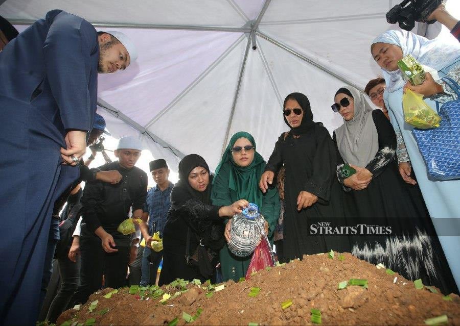 Family members and friends of the deceased pour rose water and petals during the funeral at the Raudatul Sakinah Islamic Cemetery in Taman Selasih, Kuala Lumpur. -NSTP/EIZAIRI SHAMSUDIN