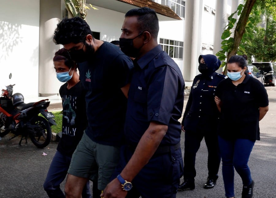  Lachhami Devi, (back, centre) and Varun Kumar (front, centre) are escorted by police officers ahead of the trial at the Shah Alam magistrate’s court. - BERNAMA PIC