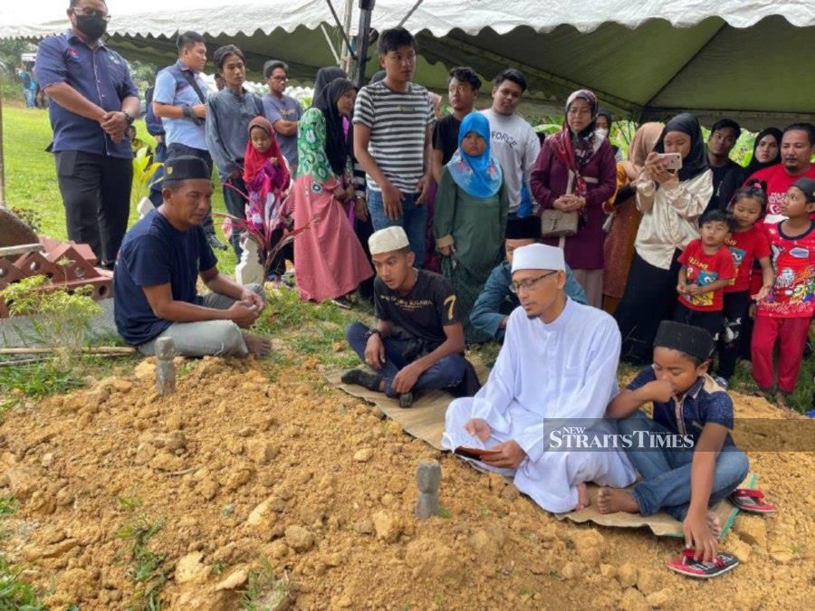 Ruslan Ahmad (left) and family members pray during the funeral at the Sungai Gatom Islamic Cemetery, Segamat. - NSTP/NUR AISYAH MAZALAN