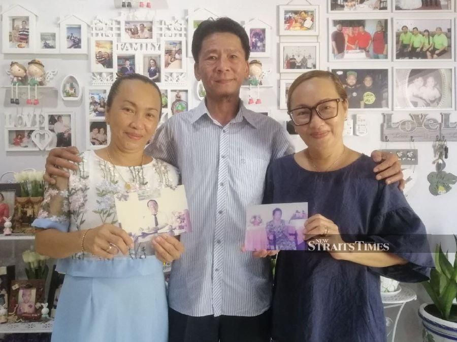 Volintine (centre) with his siblings Josephine (right) and Jennifer holding up photos of their late parents who embraced Islam. - NSTP/YUN MIKAIL.