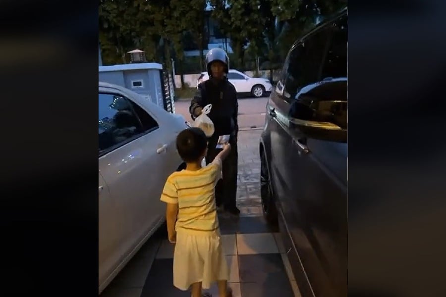 The cute and kind gesture of boy offering 'duit raya' to a food delivery rider and wishing him "Selamat Hari Raya" has touched the hearts of social media users. - Pic from TikTok tbh77_oe