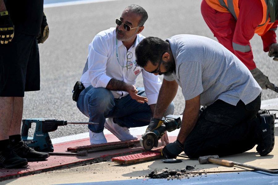 Maintenance staff repair a loose drainage grid during the third day of the Formula One pre-season testing at the Bahrain International Circuit in Sakhir. - AFP pic